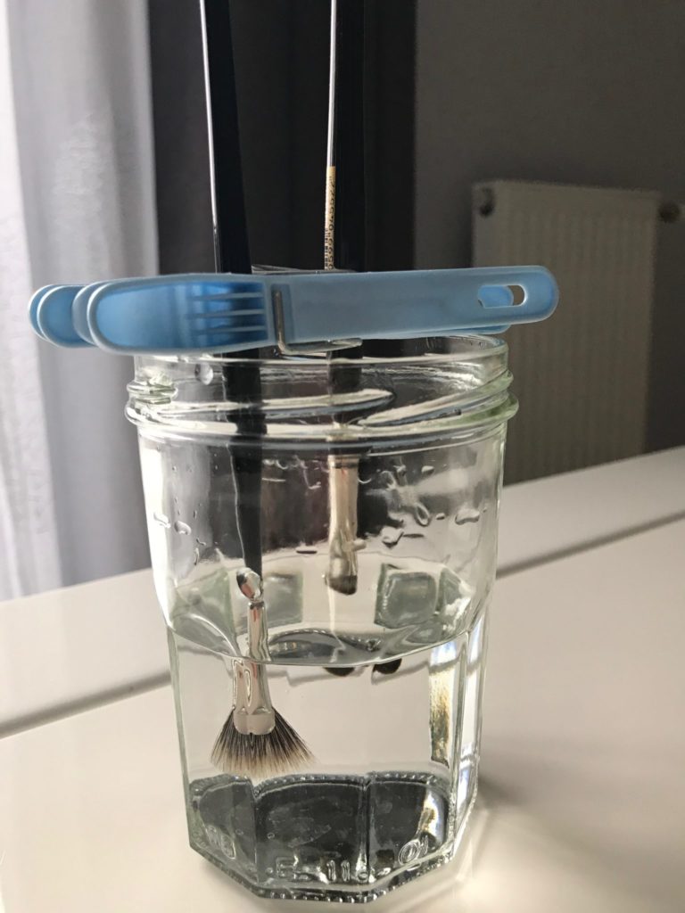 Utiliser un pot à confiture avec des pinces à linge pour maintenir la tête des pinceaux dans l'eau
